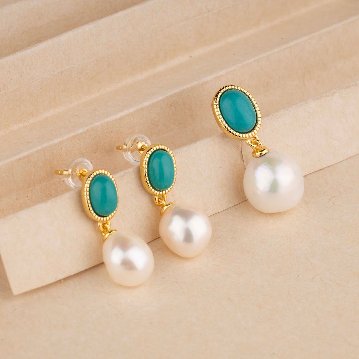 Pair of earrings with turquoise stones and pearls on a beige background